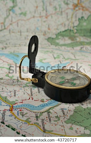 Black, military compass on the detailed map.