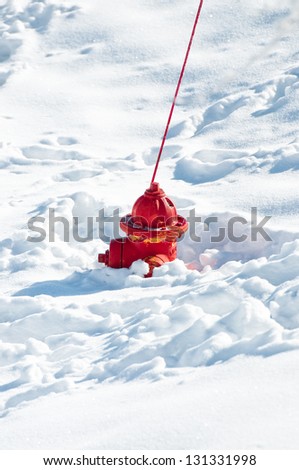 A red fire hydrant sunk in the snow.