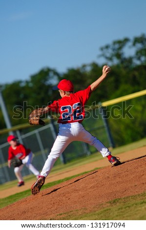 Pitcher in red jersey pitching ball.