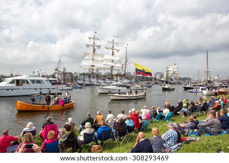 AMSTERDAM, THE NETHERLANDS - AUGUST 19, 2015: People watch ships passing by in the North Sea Canal enroute to Amsterdam to particiate in the SAIL 2015 event.