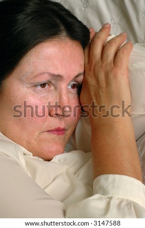 Sad older woman lying on bed, unhappy