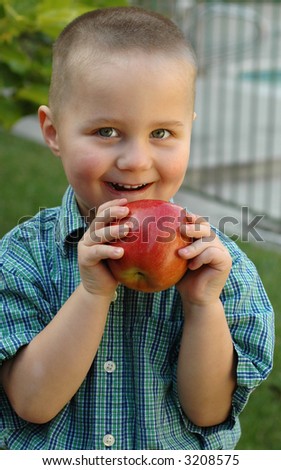 Young boy getting ready to bite into a delicious apple; good concept shot for developing healthy diet habits