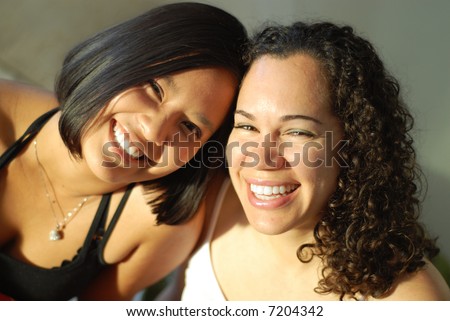 Attractive young female friends laughing and having fun; very shallow depth of field and natural light