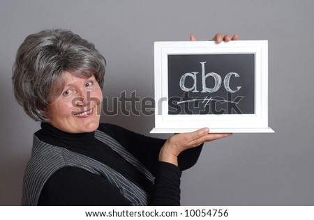 Kind older teacher with a mini blackboard and letters on it