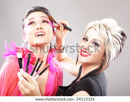 Professional makeup artist applying cosmetics to a model\'s face