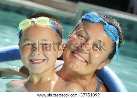 Cute shot of happy, smiling grandma and her grandson in a sparkling pool...focus on the child