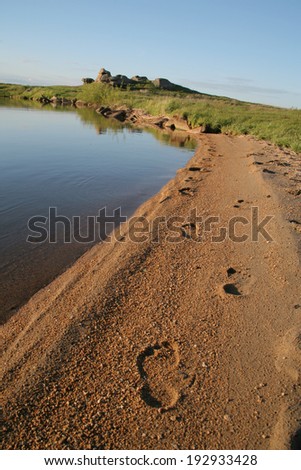 Beautiful and calming nature near the lake and footsteps on the wet sand