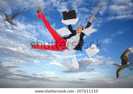 Smiling woman in an office suit holding a rope is flying in the sky with some birds