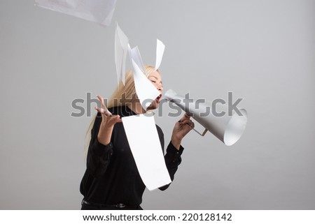 Beautiful blond businesswoman makes passionate presentation holding some papers and loudspeaker in her hands