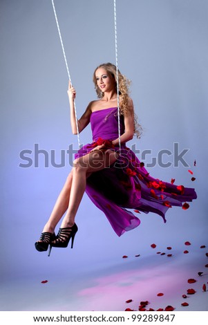 Blonde on a swing with flying rose petals