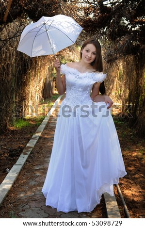 Portrait of the bride in a white dress with a diadem in hair and red rose in spring garden