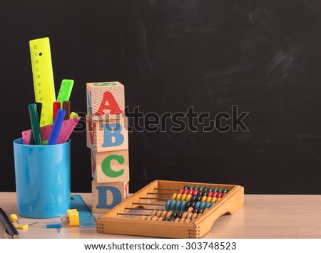 Various school supplies on wooden table against black board