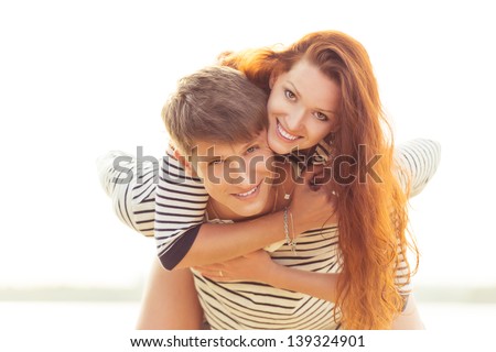 smiling man giving woman piggyback ride