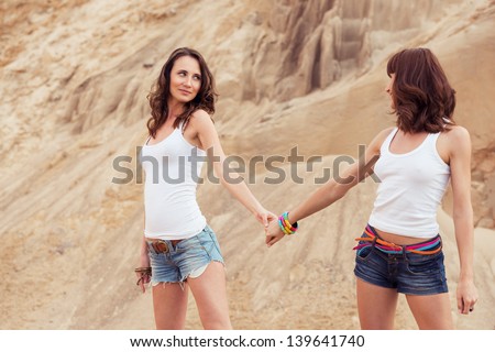 two girl holding hands on beach. outdoors woman portrait