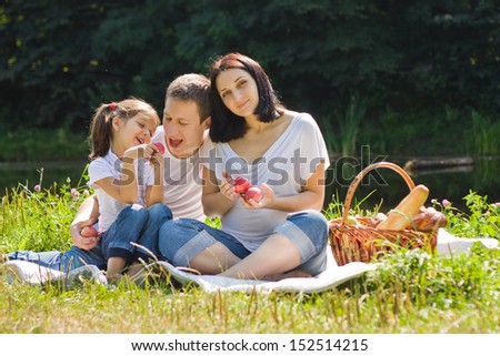 Family having picnic near lake. Backlight. Summer.