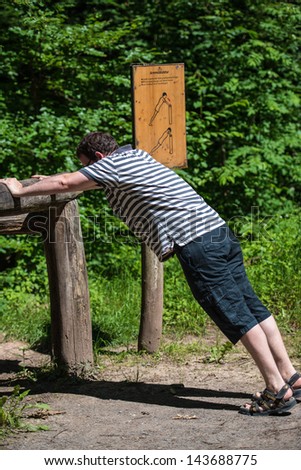 STUTTGART, GERMANY - June 16, 2013: Casual middle aged man doing gymnastics at the get-fit-trail (featuring several stations for exercising) in Botnang forest  on June 16, 2013 in Stuttgart, Germany.