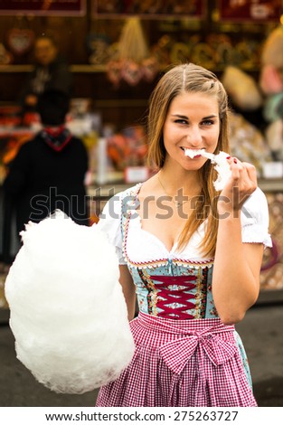 Beautiful woman wearing a traditional Dirndl dress with cotton candy floss at the Oktoberfest