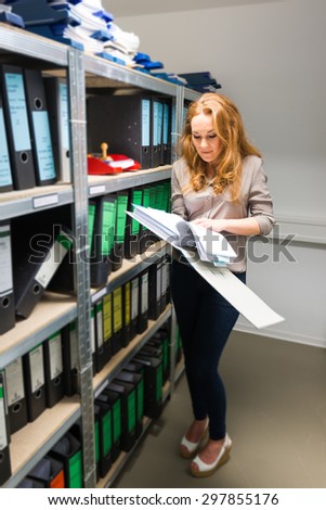 young and attractive businesswoman is searching file in company archives
