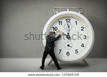 Businessman pulling a clock hand backwards