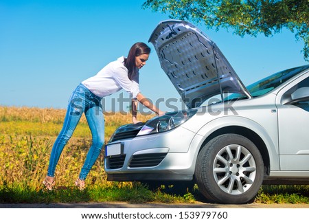 Beautiful woman trying to repair a broken car