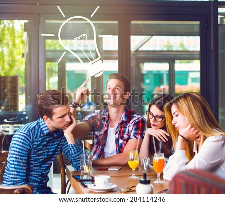 Young man with an idea, sitting with his friends in a cafe
