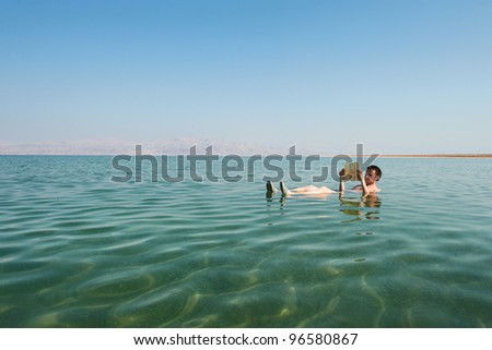 Caucasian man reads a book floating in the waters of the Dead Sea in Israel