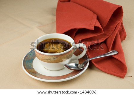 Cup of hot coffee with a small amount of cream, spoon and napkin