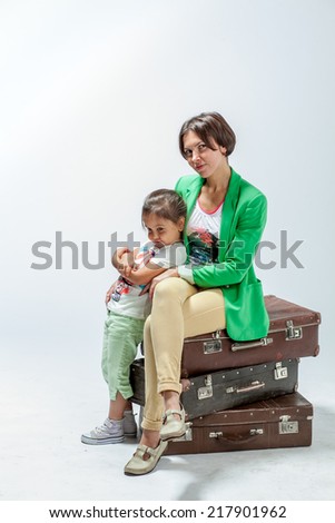 Mother and daughter sitting on suitcases in anticipation of a trip
