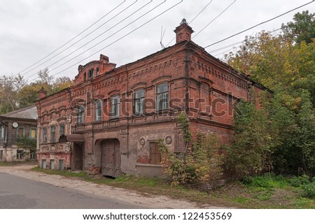 Old two-storeyed brick mansion with road before against cloudy sky background. Gorodets, Nizhegorodsky region, Russia.