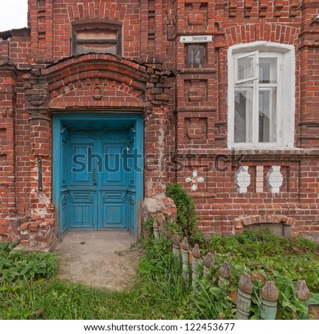 Blue wooden double door of old brick mansion with palisade before. Gorodets, Nizhegorodsky region, Russia.