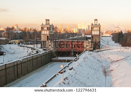 Closed shipping lock of frozen canal against city landscape background. Moscow, Russia.