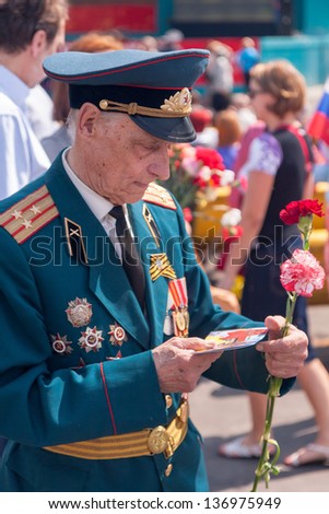 MOSCOW/RUSSIA - MAY 9: Old man veteran of WWII in uniform decorated with numerous awards looks at greeting card during festivities devoted to 65th anniversary of Victory Day on May 9, 2010 in Moscow.
