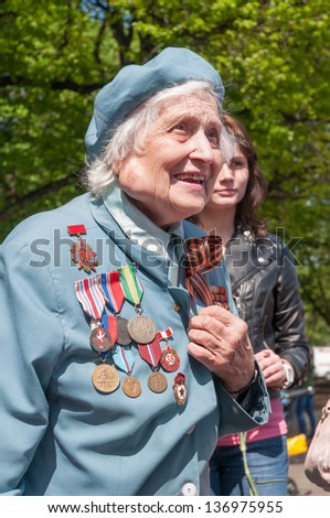 MOSCOW/RUSSIA - MAY 9: Old woman veteran of WWII in blue coat decorated with numerous orders and medals  during festivities devoted to anniversary of Victory Day on May 9, 2011 in Moscow.