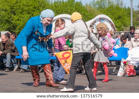 MOSCOW/RUSSIA - MAY 9: Old woman veteran of WWII in blue coat dances with little girl among other children during festivities devoted to anniversary of Victory Day on May 9, 2011 in Moscow.