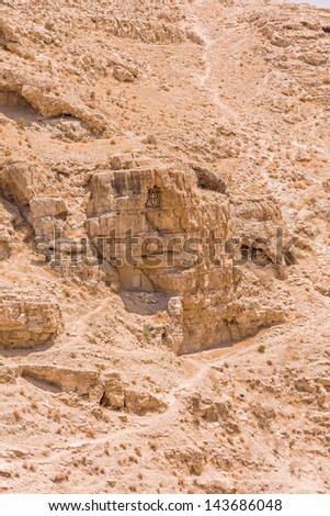 St. Sabbas the Sanctified monastic cave-cell in the mountain wall of Kidron river canyon. Viewed from Mar Saba monastery terrace in Judean desert. Palestine, Israel.