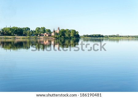 View on Vychegda River with ancient church on riverside reflecting in water against blue sky background. Solvychegodsk, Arkhangelsky region, Russia.