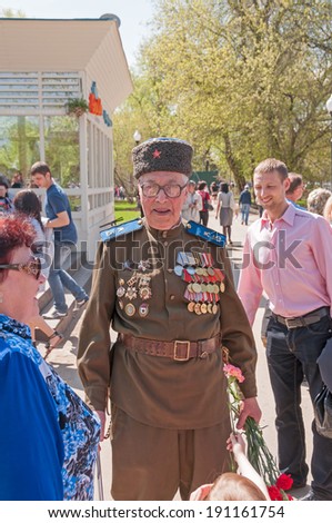 MOSCOW/RUSSIA - MAY 9: Old man veteran of WWII in cavalry uniform decorated with orders and medals stands with bunch in Gorky Park during festivities devoted to Victory Day on May 9, 2013 in Moscow.