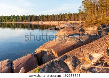 View on Onega Lake bay granite shore with pine forest at midnight sun. Besov Nos cape, Karelia Republic, Russia.