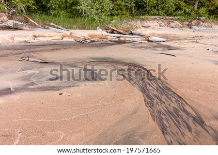 Patterned stream in layered clefts and faults in sand Onega Lake shore. Besov Nos cape, Karelia Republic, Russia.