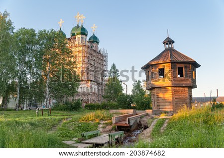 Ancient Convent of the Presentation of the Mother of God (1565) in scaffold and wooden tower over spring  at sunset. Solvychegodsk, Arkhangelsky region, Russia.