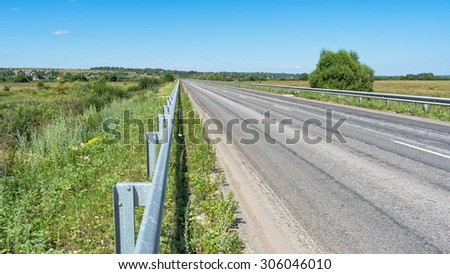 Vanishing straight highway with metal rails along. Kozelsk, Kaluzhsky region, Russia.