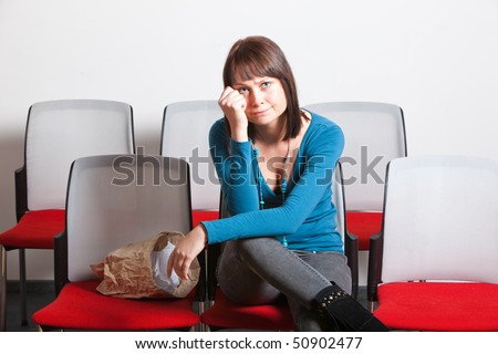 sad young woman sitting and getting emotional while watching movie, holding hand on her cheek, horizontal shot