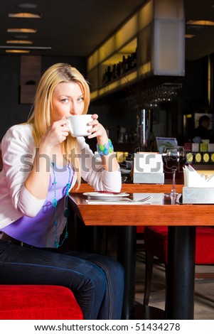 A Young Woman Sitting At A Table In A Restaurant. She Is Drinking A ...