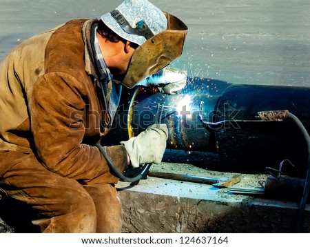Metal worker welds two pieces of metal together