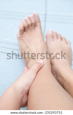 Woman holding left ankle while sitting down to show pain in the ankle area