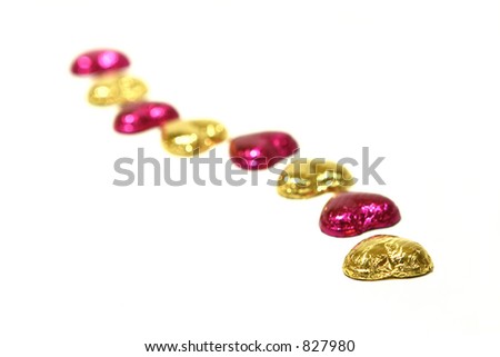 Hearts in a line: An arrangement of gold and fuchsia foil covered heartshaped chocolate in a line
