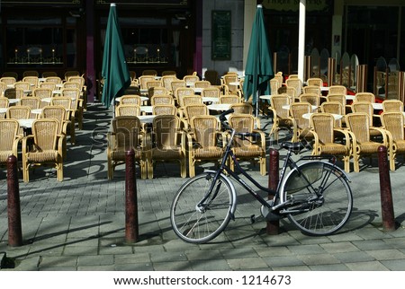 Alone but strong: Concept of being alone but powerful,admired by others - A lone bike parked on a metal post, seemed watch by rows of wicker chairs representing people