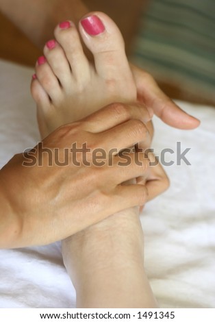 A woman receiving foot reflexology as part of a holistic massage treatment