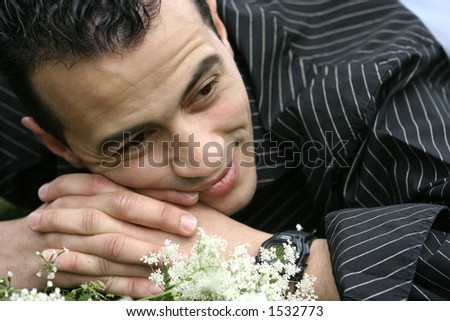 A young man laying down in field of flowers, in touch with his feelings and emotion. Concept : Modern man