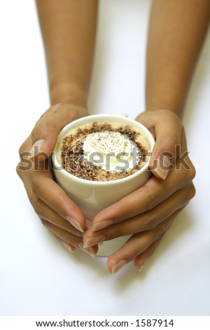 A feminine pair of hands holding a hot cup of cappucino with cream on top and sprinkle of chocolate powder